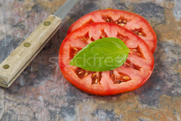 Single basil leaf and sliced tomato with knife on real stone boa Stock photo © tab62