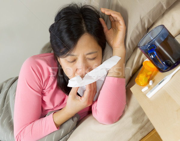 Mature woman wiping her nose with tissue while lying in bed  Stock photo © tab62