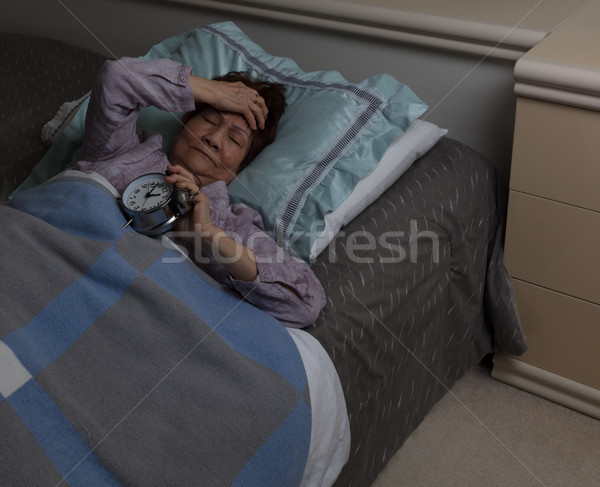 senior woman in pain holding her alarm during sleepless night wh Stock photo © tab62