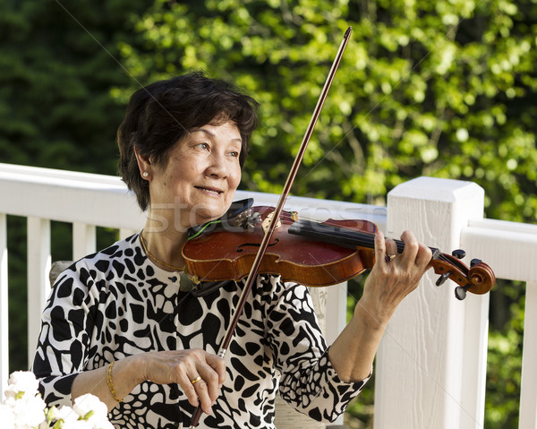 Senior woman sitting down while playing her violin outdoors  Stock photo © tab62