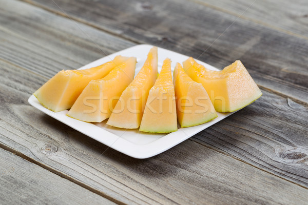 Fresh Melon Slices on White Plate with rustic wood underneath  Stock photo © tab62