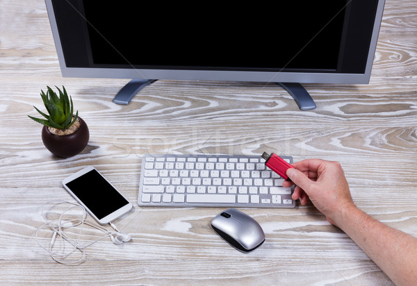 Hand holding data thumb drive with office desktop setup in backg Stock photo © tab62