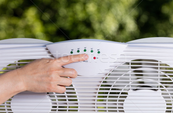Hand adjusting window fan to cool down room in home during hot w Stock photo © tab62