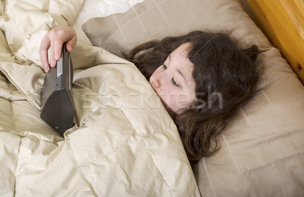 Young girl over sleeps and looks at alarm clock in surprise  Stock photo © tab62