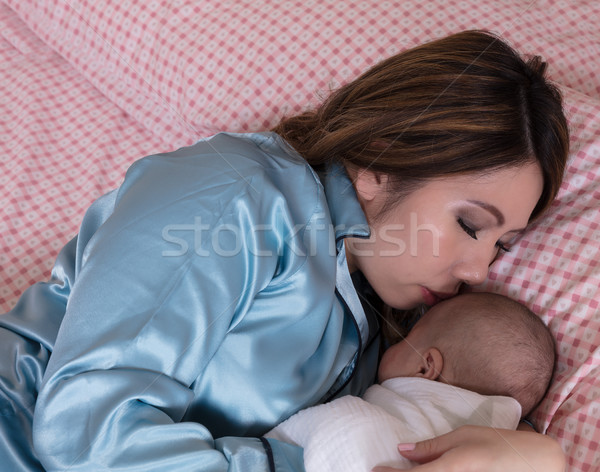 Mom closely holding her infant son while sleeping in bed  Stock photo © tab62