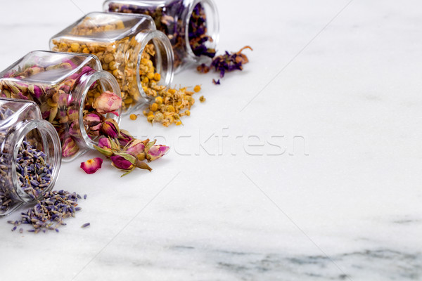 Spices and herbs in small glass jars pouring onto marble stone b Stock photo © tab62