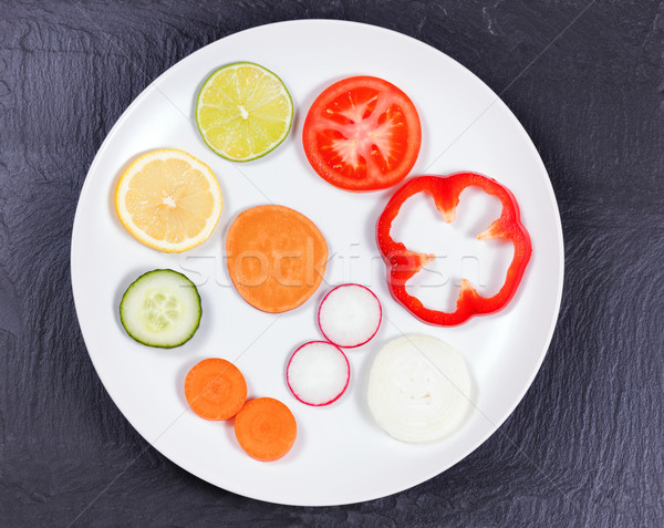 Circle of sliced fruit and vegetables in white plate on natural  Stock photo © tab62
