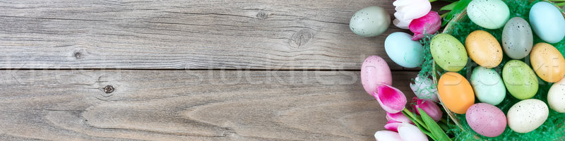 Stock photo: Wicker basket filled with eggs and tulips on weathered wooden bo