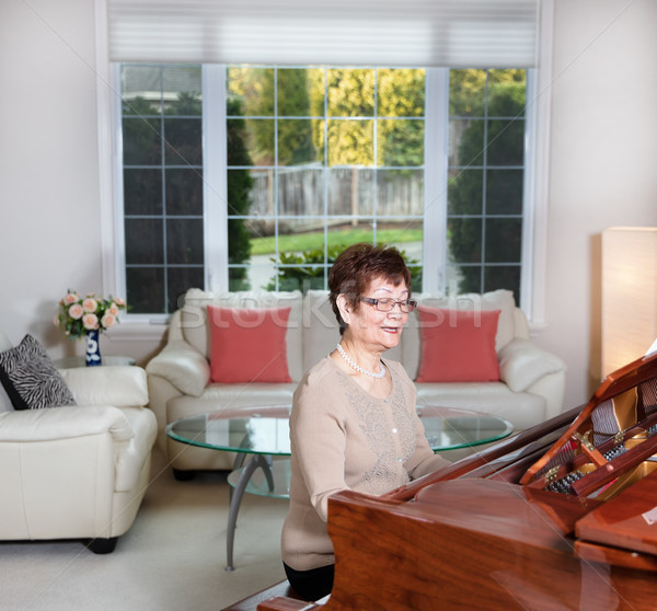 Senior woman playing her piano with happiness Stock photo © tab62