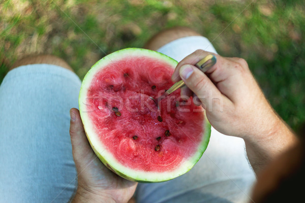 A young man is eating a watermelon with a spoon. The concept of  Stock photo © TanaCh