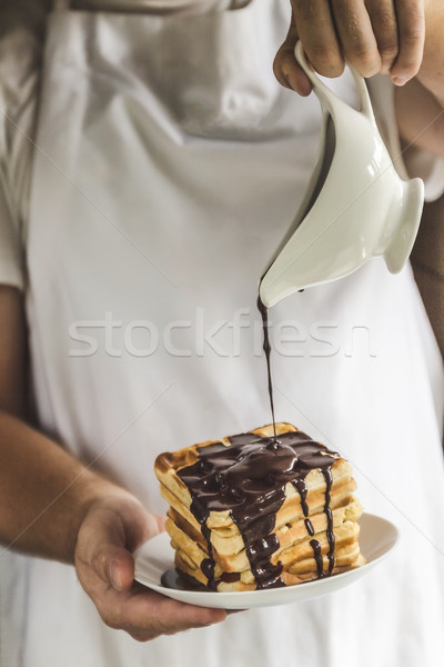 The chef in his hands holds a plate with Belgian waffles and pou Stock photo © TanaCh