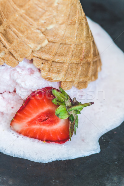 Strawberry ice cream in a waffle cone inverted and melted agains Stock photo © TanaCh