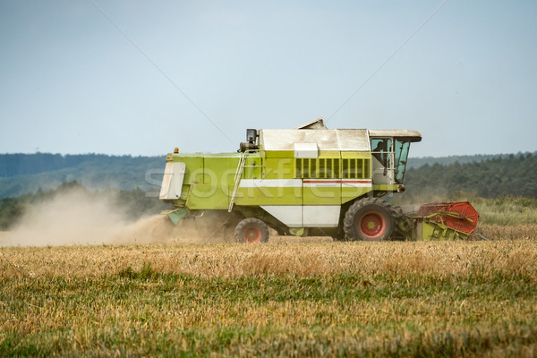 Stock photo: combine harvester that is harvesting wheat with dust straw in the air