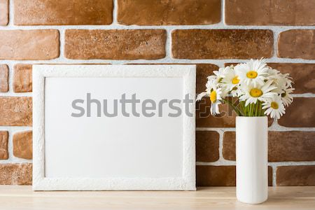White frame mockup with daisy bouquet near exposed brick wall Stock photo © TasiPas