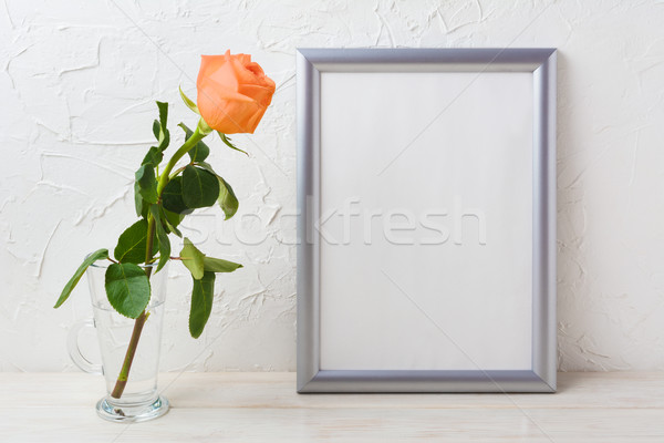 Silver frame mockup with orange-apricot rose in glass vase Stock photo © TasiPas