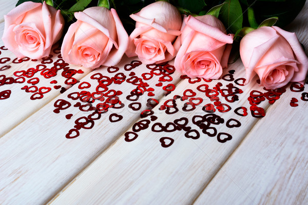 Stock photo: Fall in love concept with pale pink roses and small red hearts 