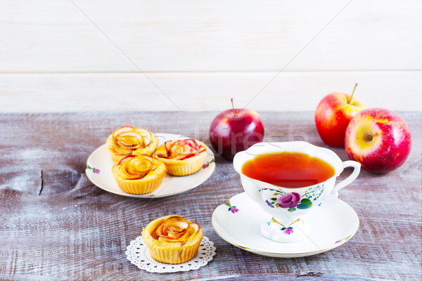 Cup of tea and apple roses shaped muffins on rustic wooden table Stock photo © TasiPas