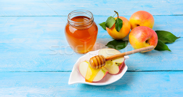 Honey jar and apple slices with honey on blue wooden background Stock photo © TasiPas