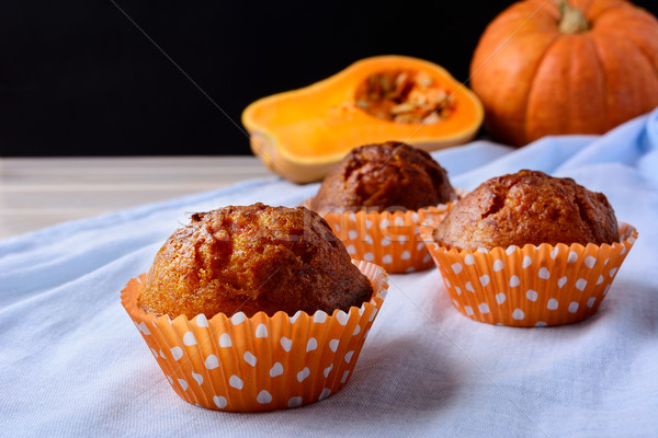 Pumpkin muffins in the orange wrappers on the blue napkin Stock photo © TasiPas
