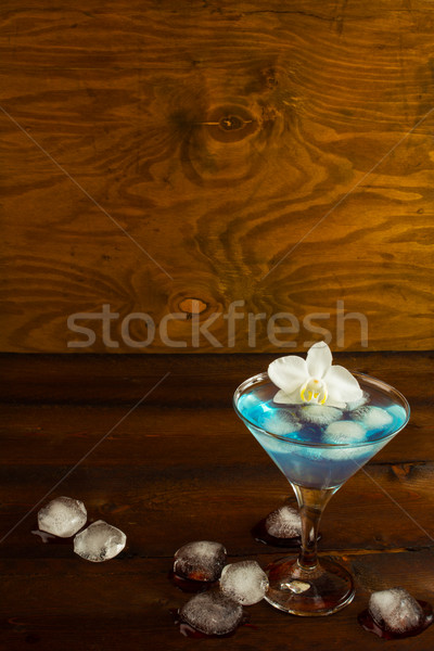 Stock photo: Blue cocktail in a martini glass with white orchid, vertical, co
