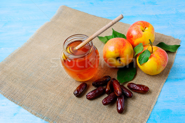 Honey jar, dates and apples on blue wooden background Stock photo © TasiPas