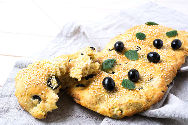 Italian bread focaccia with olive and herbs on linen napkin Stock photo © TasiPas