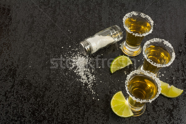 Gold tequila with lime on black background, top view Stock photo © TasiPas