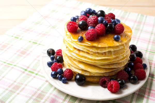 Stack of pancakes with honey, blueberry, raspberry and blackcurr Stock photo © TasiPas