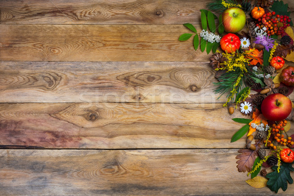 Fall background with pumpkin and green leaves on wooden table  Stock photo © TasiPas