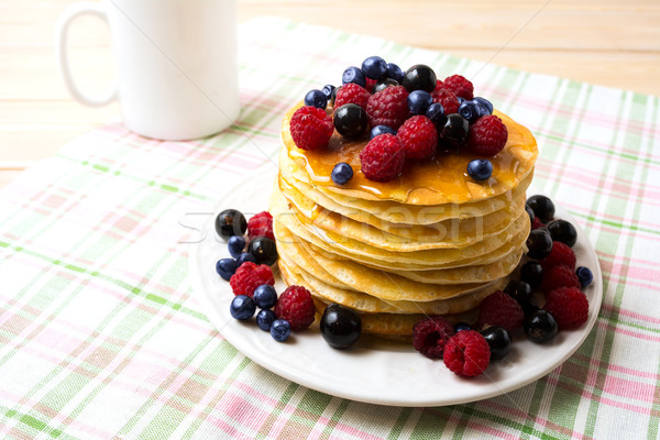 Breakfast pancakes with honey and fresh berries and coffee mug Stock photo © TasiPas