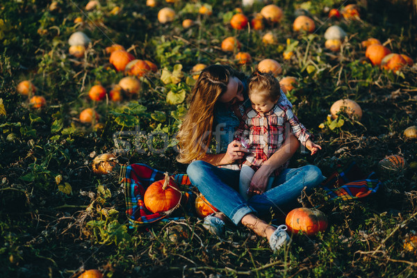 Stock photo: mother and daughter on a field with pumpkins