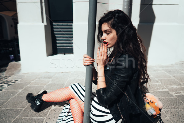 Beautiful fashionable lady sitting on old street Stock photo © tekso