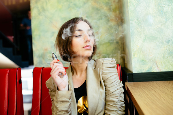 girl sits and smokes electronic cigarette Stock photo © tekso