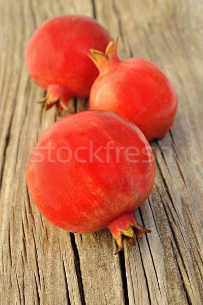 Three fresh red pomegranetes on a wooden board Stock photo © tish1