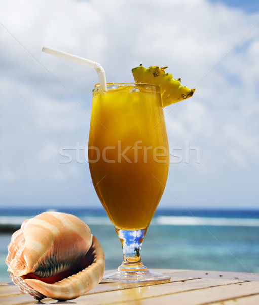 Tropical fruit cocktail and sea shell with ocean in background Stock photo © tish1