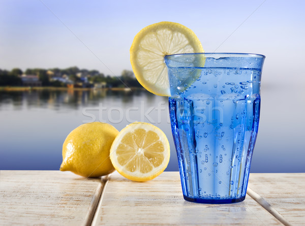 a Blue glass with sparkling water and lemon on a wooden deck overlooking the calm water of a tropica Stock photo © tish1