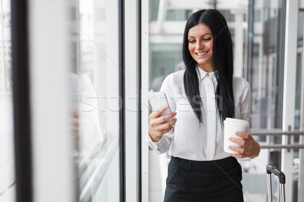Successful business woman with coffee and smartphone in an office setting Stock photo © tommyandone