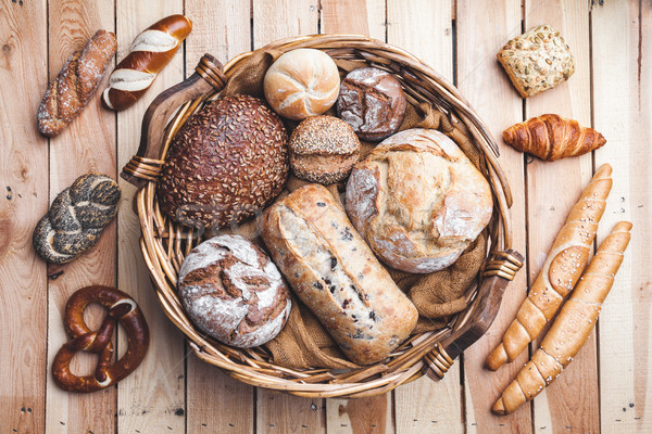 Stock photo: A basket full of delicious fresh bread on wooden background