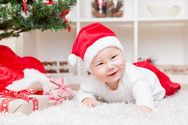 Cute baby in a Santa hat next to Christmas tree with presents Stock photo © tommyandone