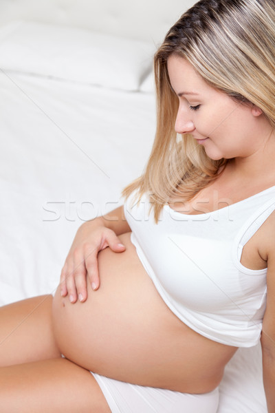 Pregnant woman sitting on bed and looking on belly Stock photo © tommyandone