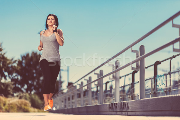 Stock photo: City workout. Beautiful woman running in an urban setting