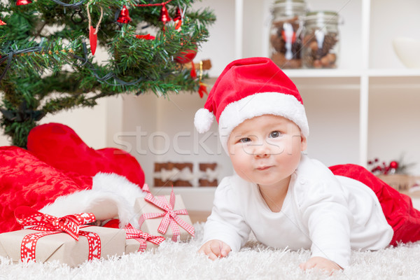 Cute baby in a Santa hat next to Christmas tree with presents Stock photo © tommyandone