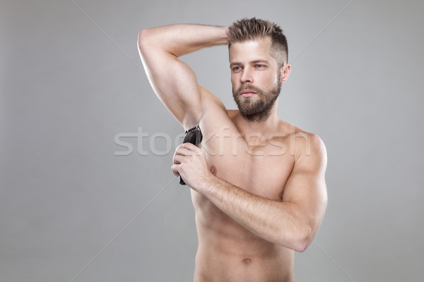 Handsome Bearded Man With A Trimmer Shaving Off Body Hair Stock