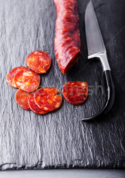 Spanish chorizo with a knife on a stone plate. Stock photo © user_11224430