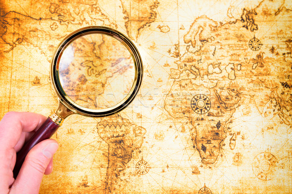 Stock photo: Old map and magnifying glass in a hand