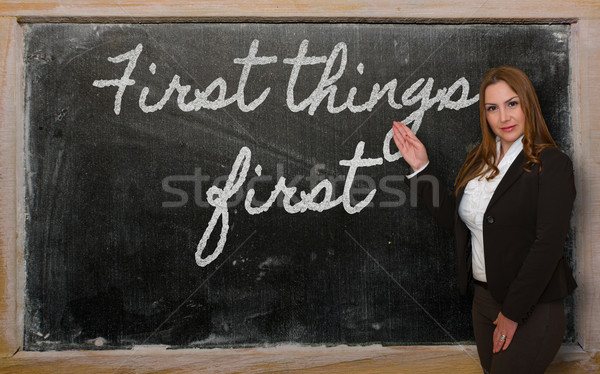 Stock photo: Teacher showing First things first on blackboard