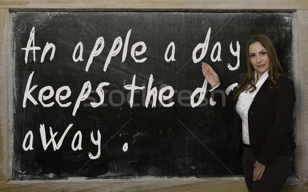 Teacher showing An apple a day keeps the doctor away on blackboa Stock photo © vepar5
