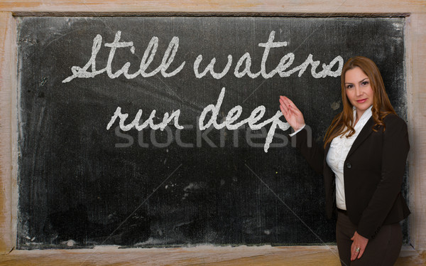 Teacher showing Still waters run deep on blackboard Stock photo © vepar5