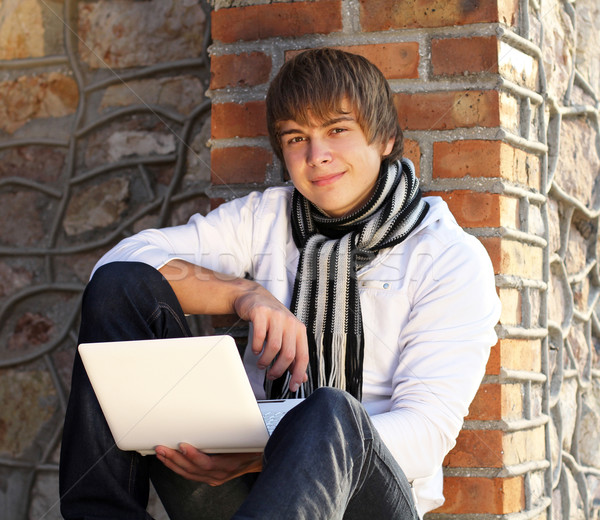 Young man with laptop leaning against the brick wall Stock photo © Victoria_Andreas