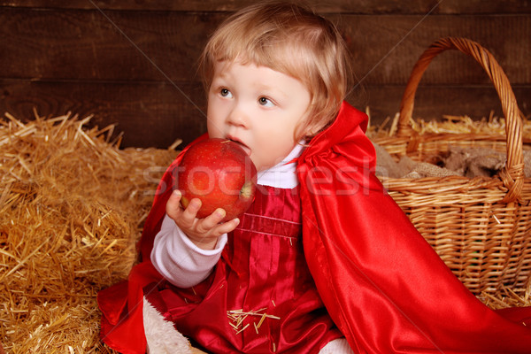 Little girl is sitting on pile of straw eating apple. Little Red Stock photo © Victoria_Andreas